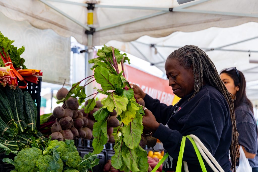 A shopper selecting fresh beets at the Crenshaw Farmers Market in the Los Angeles Sentinel's anniversary story
